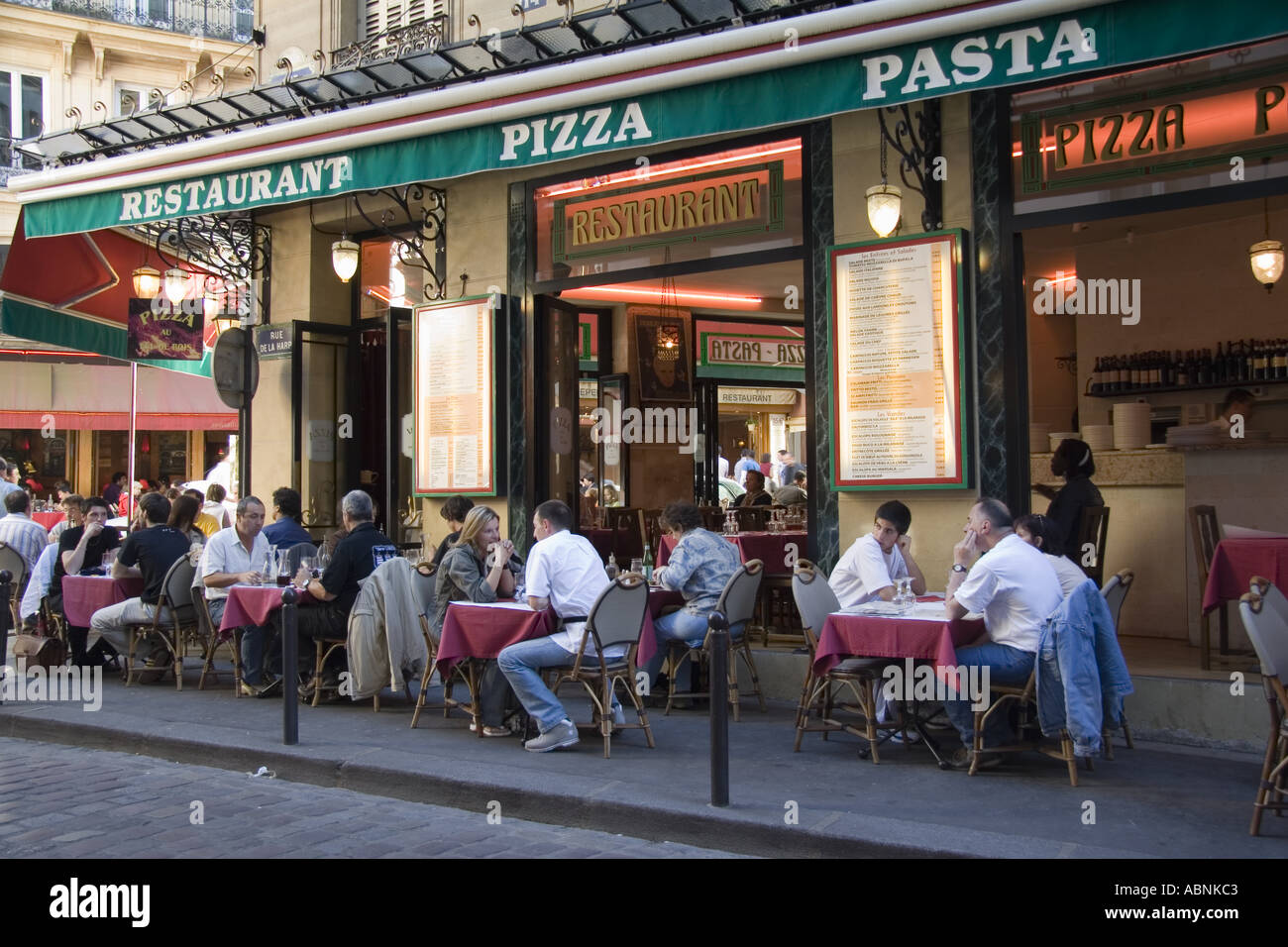 Persone cenare al marciapiede tavoli ad una pizza e pasta ristorante su Rue De La Harpe vicino a Place St Michel nel Quartiere Latino Foto Stock