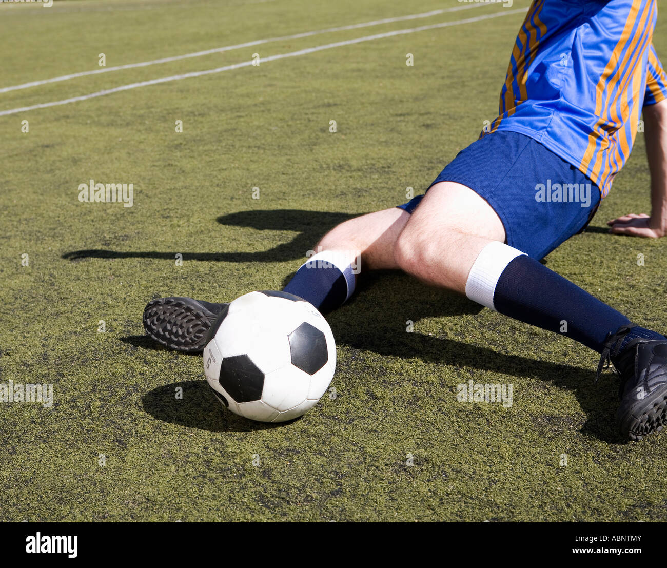 Giocatore di calcio calciare la palla dal pavimento Foto Stock