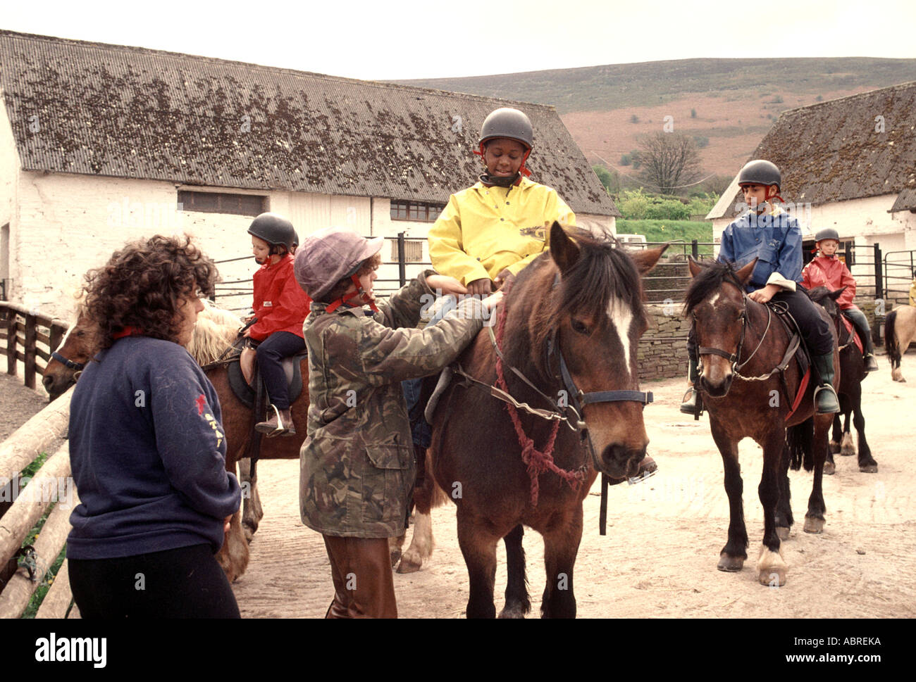 I bambini vengono insegnati horesback a cavallo di una scuola primaria avventura gita in campagna Foto Stock