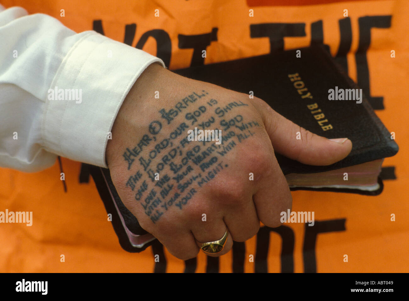 Tatuaggio religioso su mans Hand, predicatore fanatico di strada tiene in mano un bible Deuteronomy Verses 6:4–5 Glasgow, Scozia maggio 1982. 1980S UK HOMER SYKES Foto Stock
