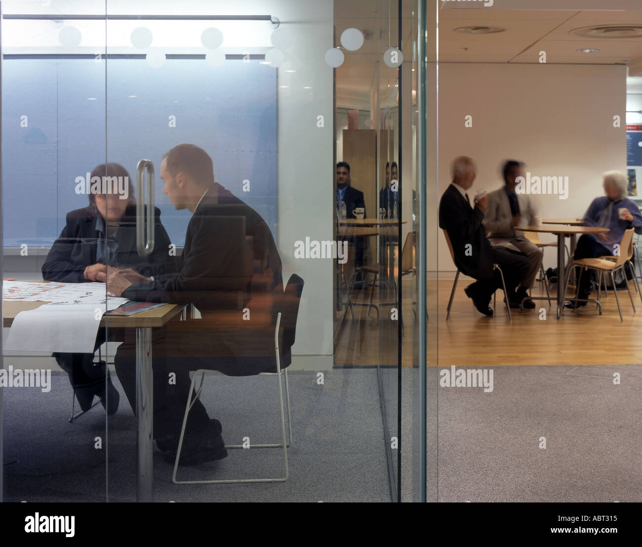 Vita in ufficio e di interni. Due imprenditori in sala riunioni e ufficio lavoratori in background. Foto Stock