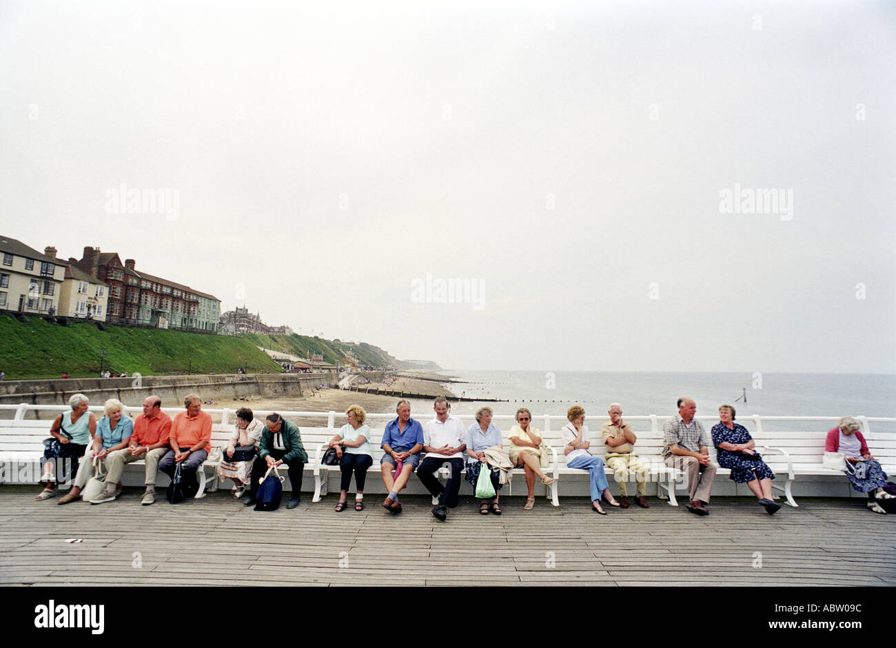 I visitatori a Cromer NORFOLK REGNO UNITO a sedersi su una panca sul molo Foto Stock