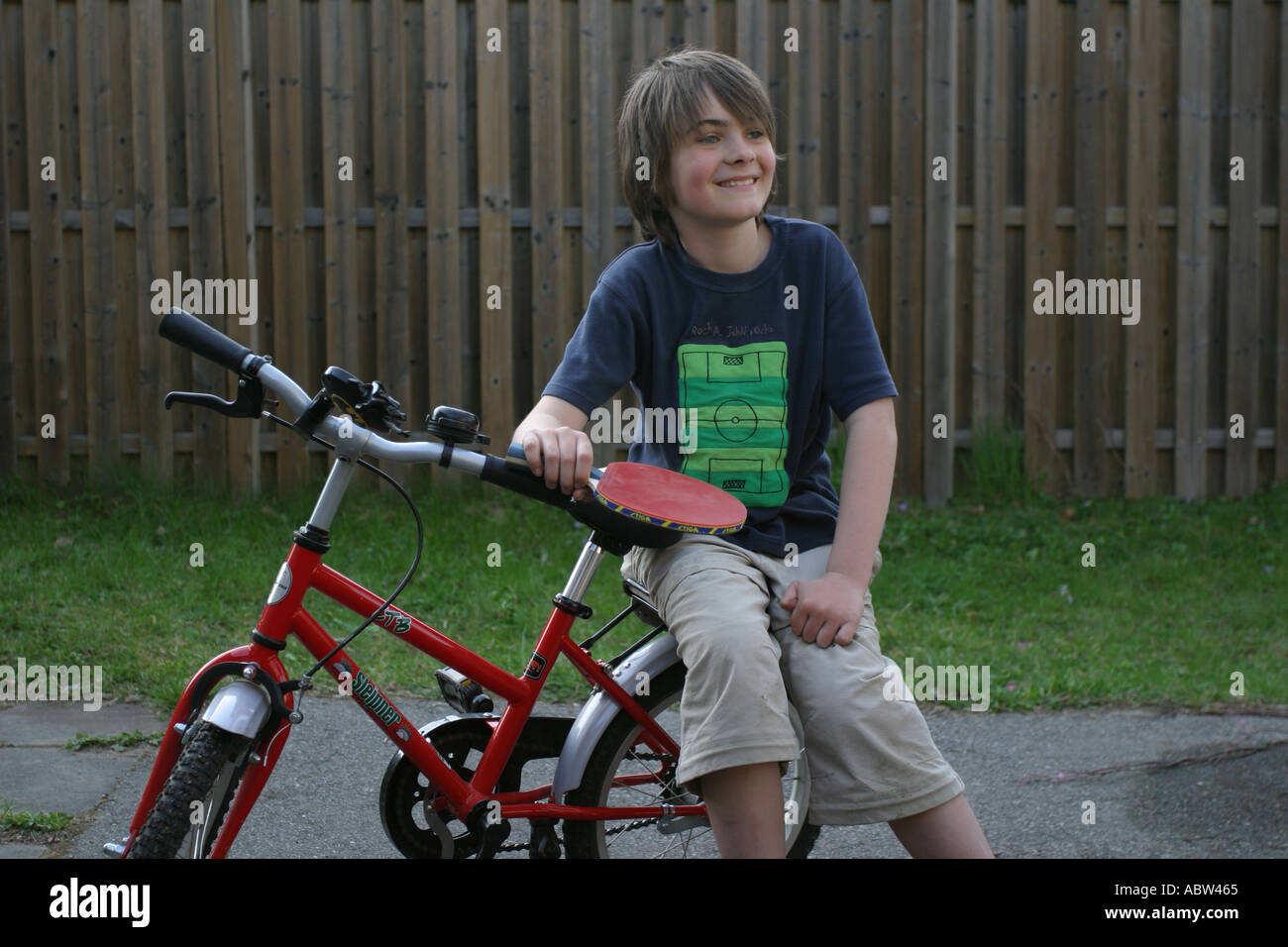 Un ragazzo tenendo un ping pong bat seduto su una bici a casa, Svezia. Foto Stock