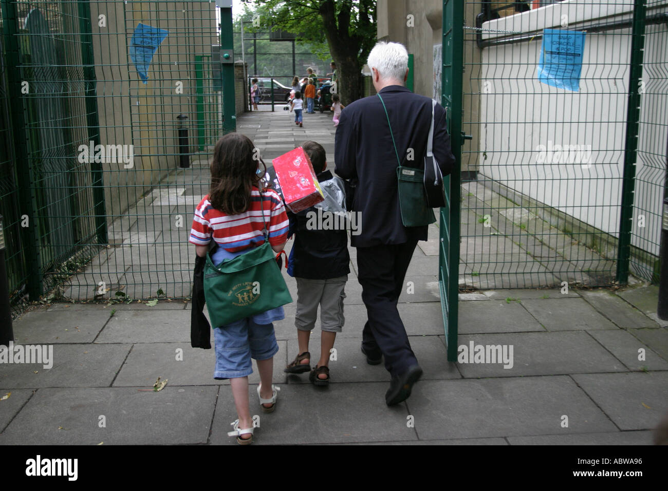 Un padre lascia la scuola nel pomeriggio con i suoi due figli, Betty Layward junior school di Londra, Regno Unito. Foto Stock