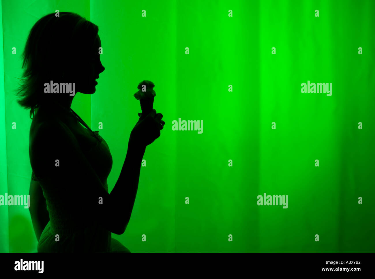 Silhouette di una donna che regge un cono gelato su un vivace sfondo verde, USA. Foto Stock