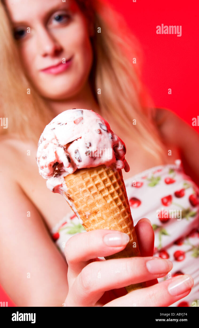 Donna che indossa un abito a motivo di ciliegio che guarda la fotocamera mentre tiene in mano un cono di gelato alla ciliegia. STATI UNITI. Foto Stock