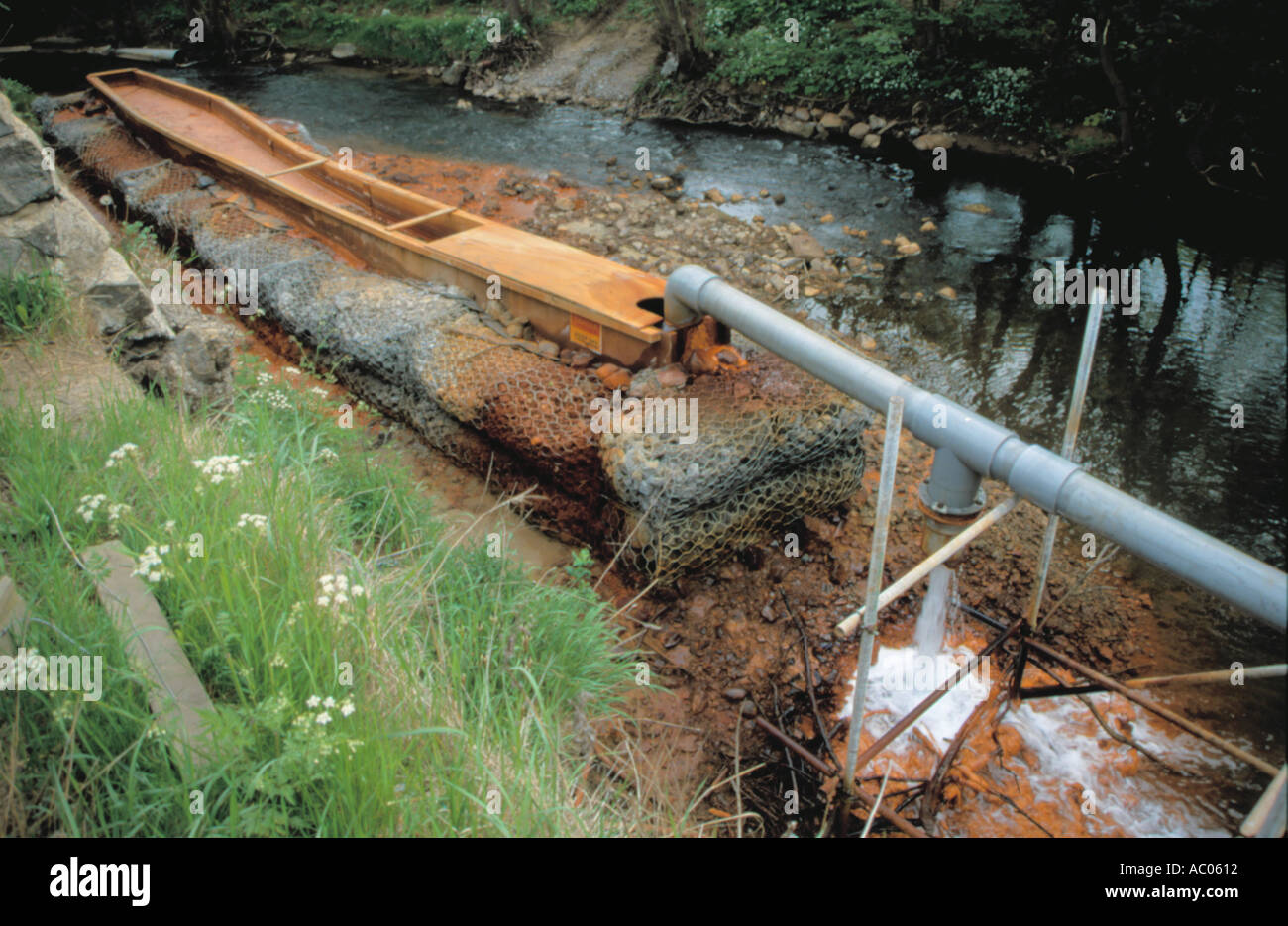 Rimozione di ocra rossa inquinamento da un fiume; inquinamento del Hagg Beck, a Skinningrove, Cleveland, Inghilterra, Regno Unito. Foto Stock