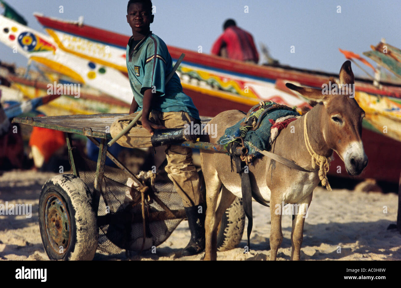 Un puledro di asino carrello conducente attende per scaricare barche da pesca a Plage des Pecheurs Fishermens Beach Foto Stock