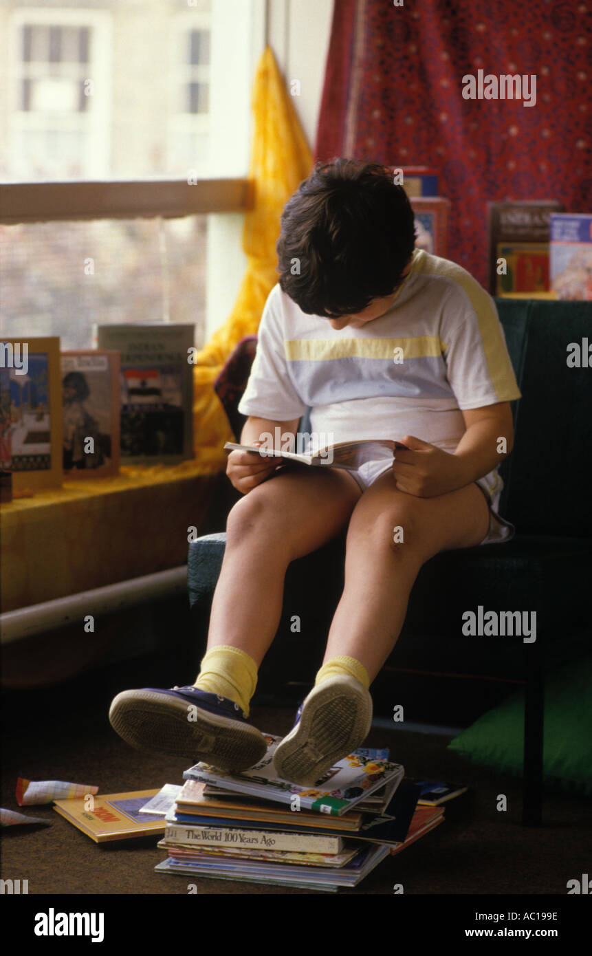 Scuola elementare 1980 Regno Unito. Ragazzo che legge un libro da solo concentrando Londra Inghilterra 1980 OMERO SYKES Foto Stock