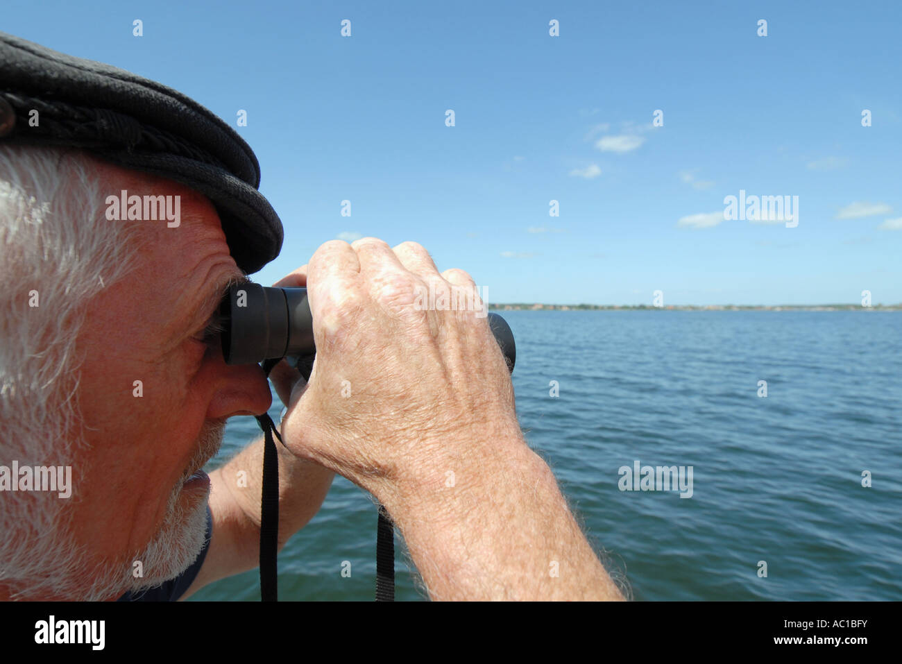 Uomo maturo cerca attraverso il binocolo sul mar Baltico Foto Stock