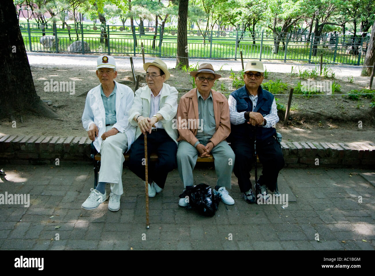 Quattro anziani coreano uomini seduti su una panchina nel parco, Seoul, Corea del Sud Foto Stock