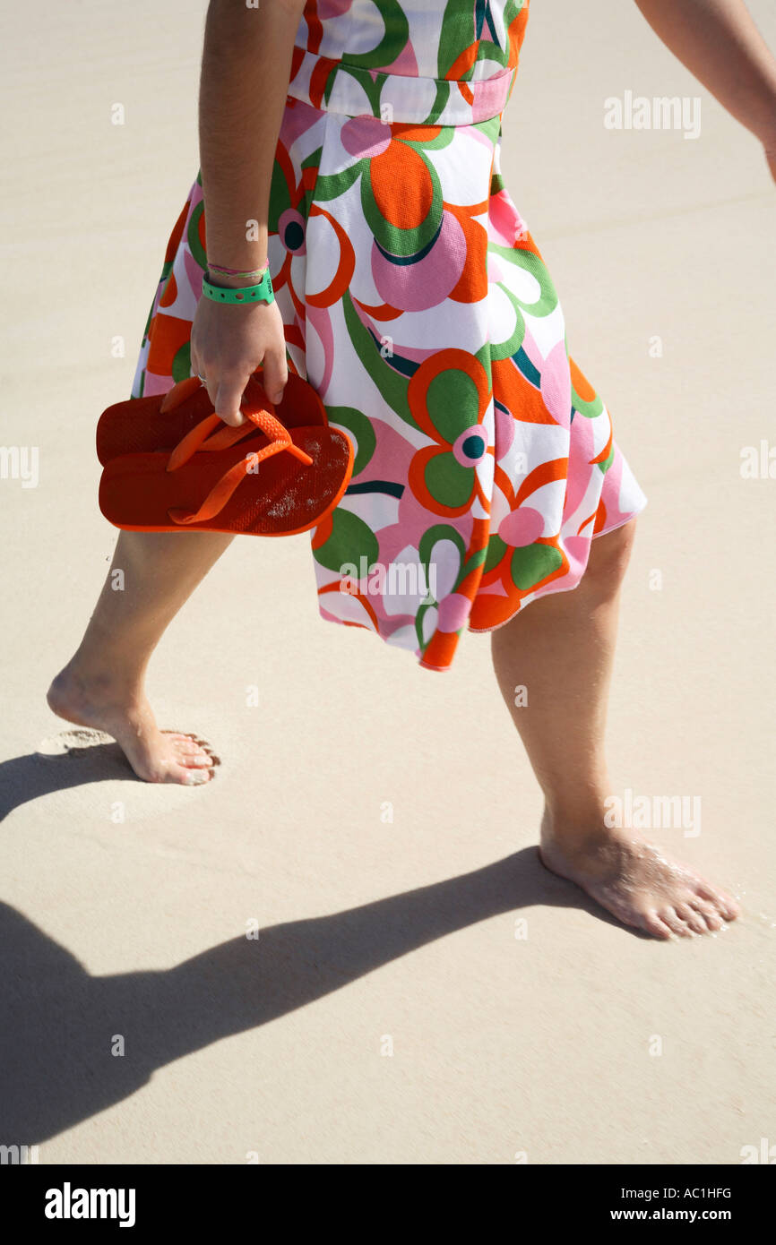 Donna sulla spiaggia, azienda scarpe di gomma Foto stock - Alamy