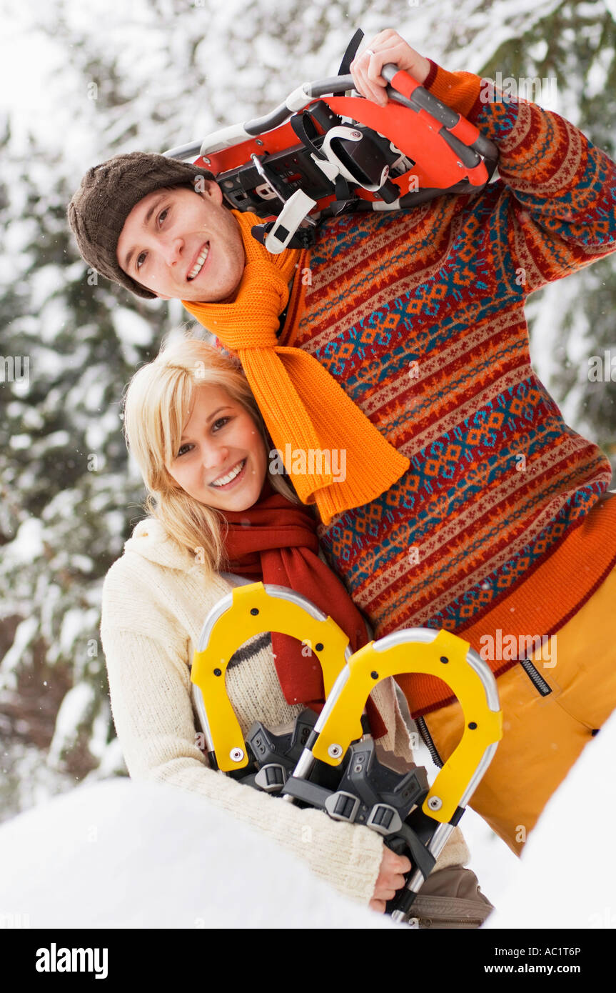 Giovane abbracciando, donna tenendo le racchette da neve Foto Stock