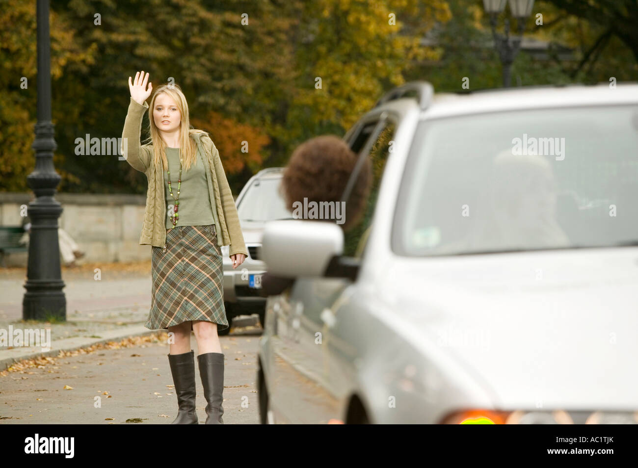 Ragazza in piedi in strada, agitando la mano Foto Stock