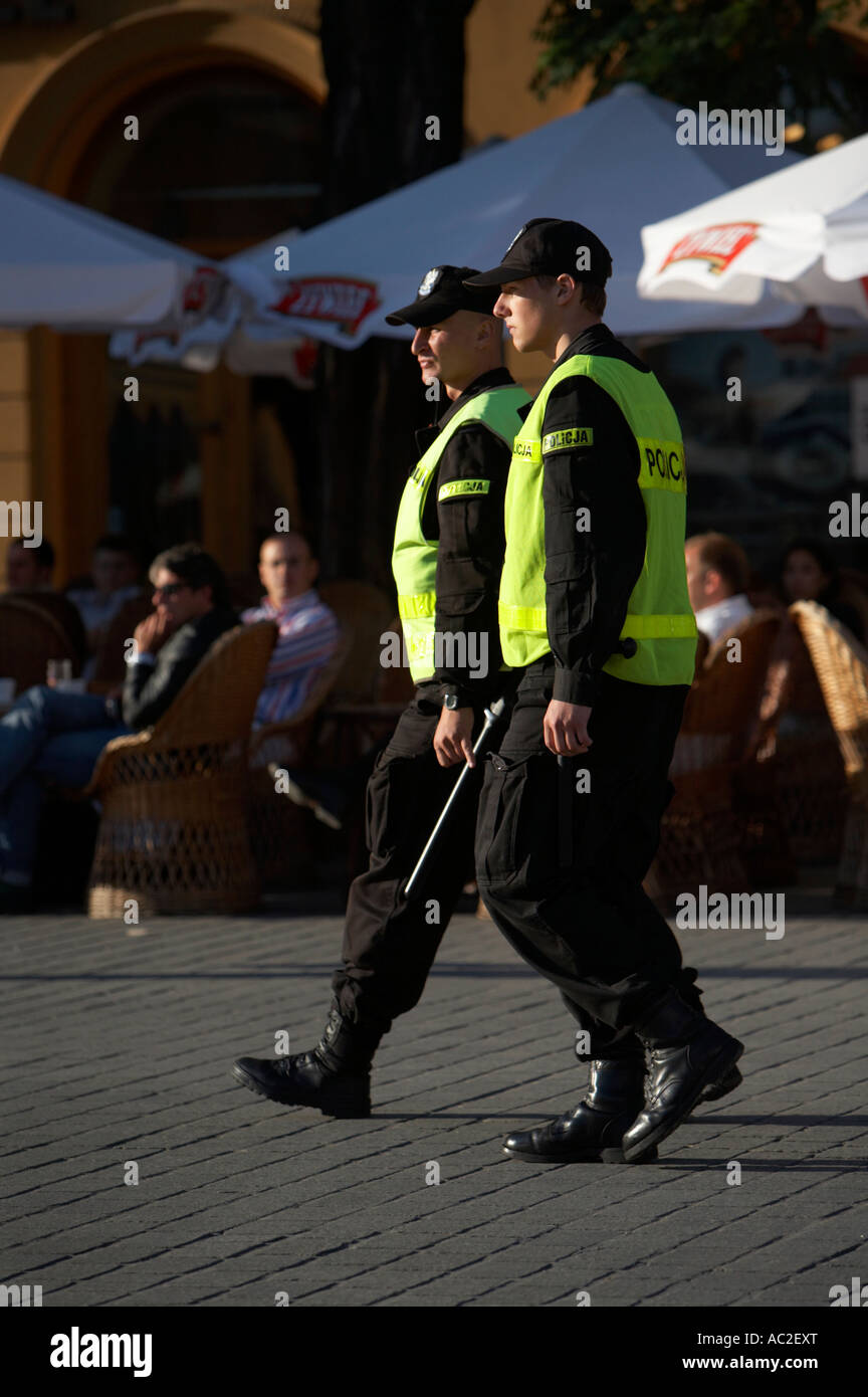 Due polacco degli ufficiali di polizia di pattuglia di fronte street cafe in Rynek Glowny piazza della città di Cracovia Foto Stock