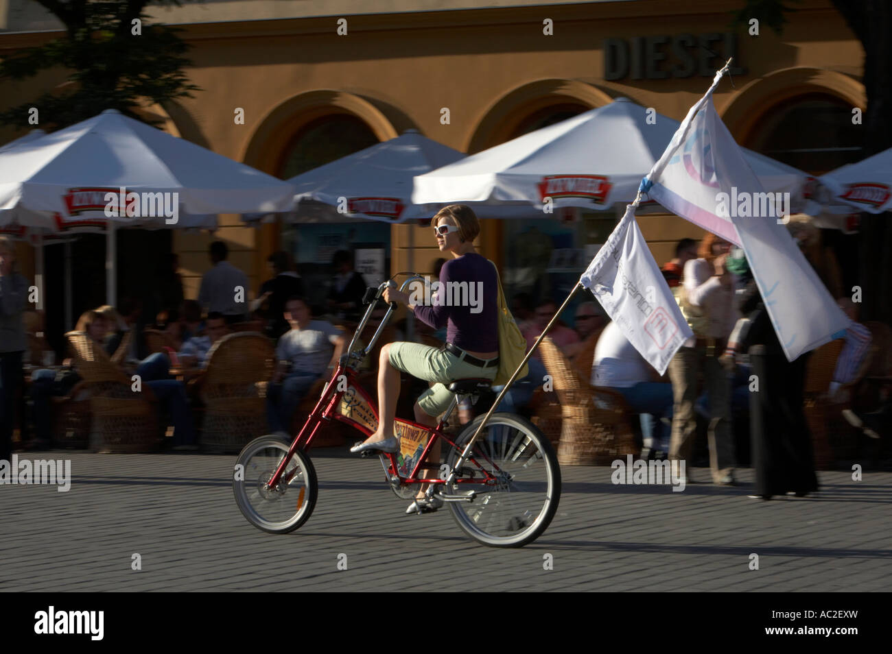 Ragazza sulla bicicletta del trinciatore con la bandiera in bicicletta attraverso Rynek Glowny town square Cracovia pubblicità servizi turistici locali Foto Stock