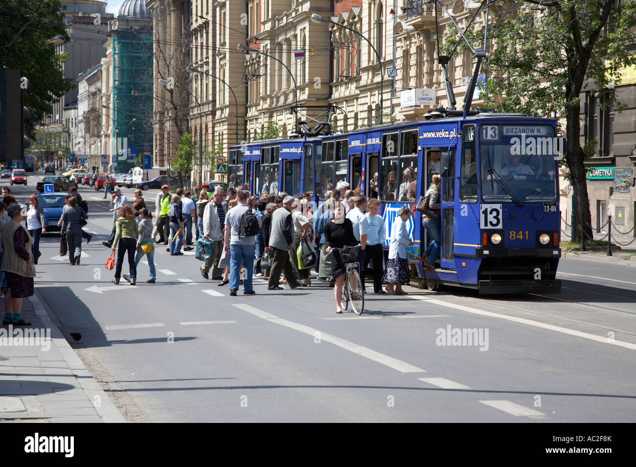 I pedoni attraversano la strada in ora di punta alla scheda elettrica di trasporto pubblico tram Cracovia Foto Stock