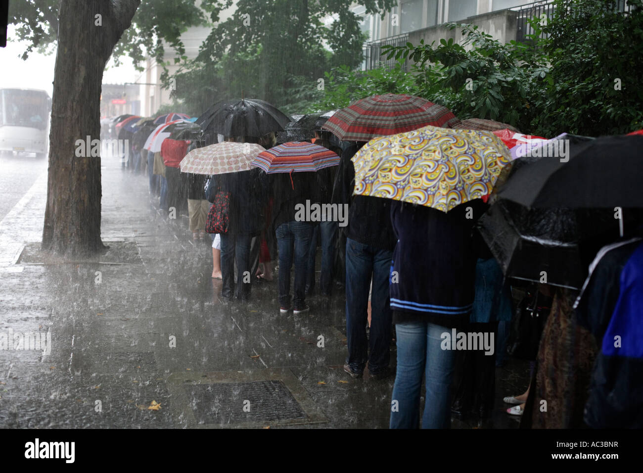 La gente in coda in una pioggia di estate storm per Madame Tussaud su Marylebone Road a Londra Foto Stock