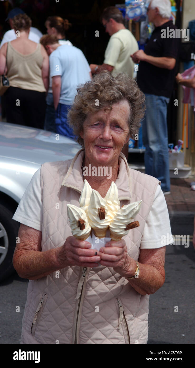 Una signora anziana con una manciata di gelato cornette in Littlehampton REGNO UNITO Foto Stock