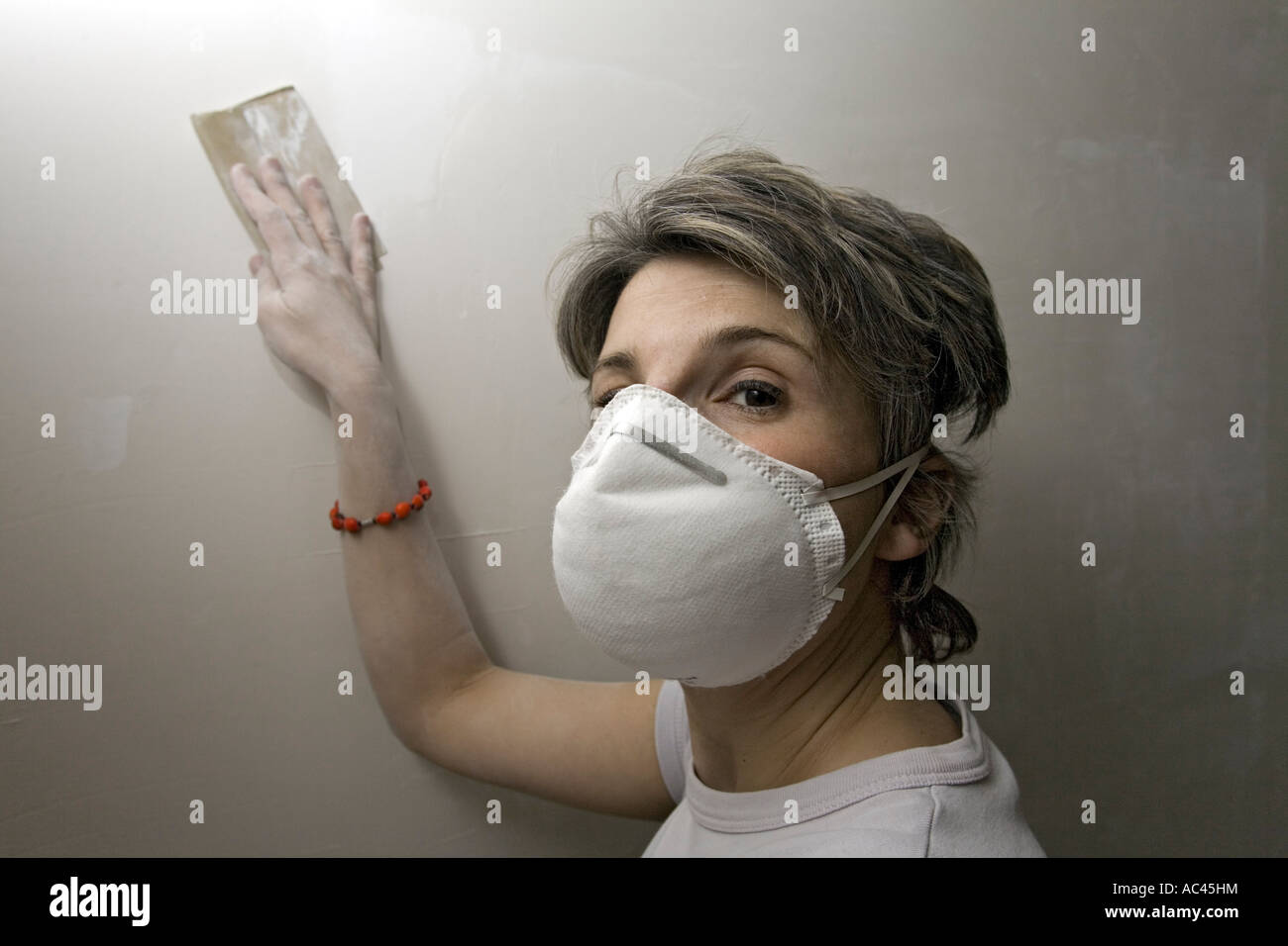 Una giovane donna di levigatura dell un intonaco parete (Francia). Jeune femme ponçant onu recouvert Mur de plâtre (Francia). Foto Stock