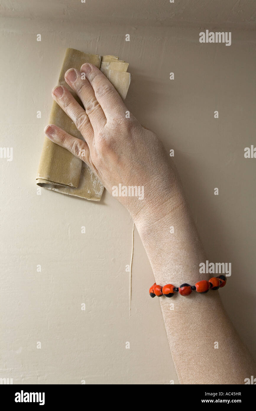Una donna di carteggiatura a mano giù il gesso di una parete (Francia). Principali de femme ponçant le plâtre d'onu mur (Francia). Foto Stock