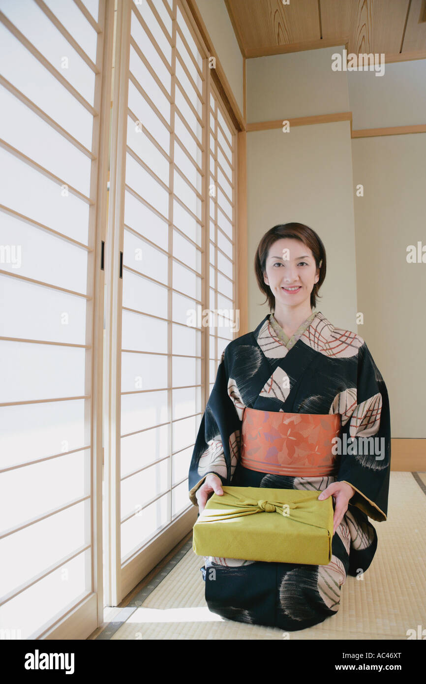 Giovane donna in kimono seduto sul pavimento Foto Stock