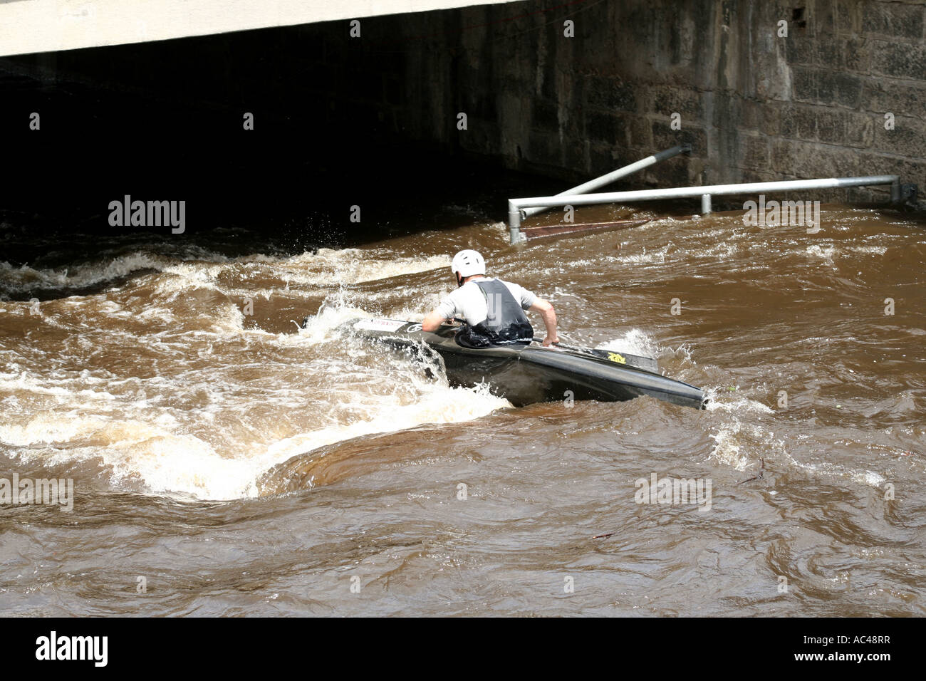 Un kayak che naviga in acque turbolente sotto un ponte a Karlovy Vary, Repubblica Ceca, mostrando un'emozionante avventura di sport acquatici. Foto Stock