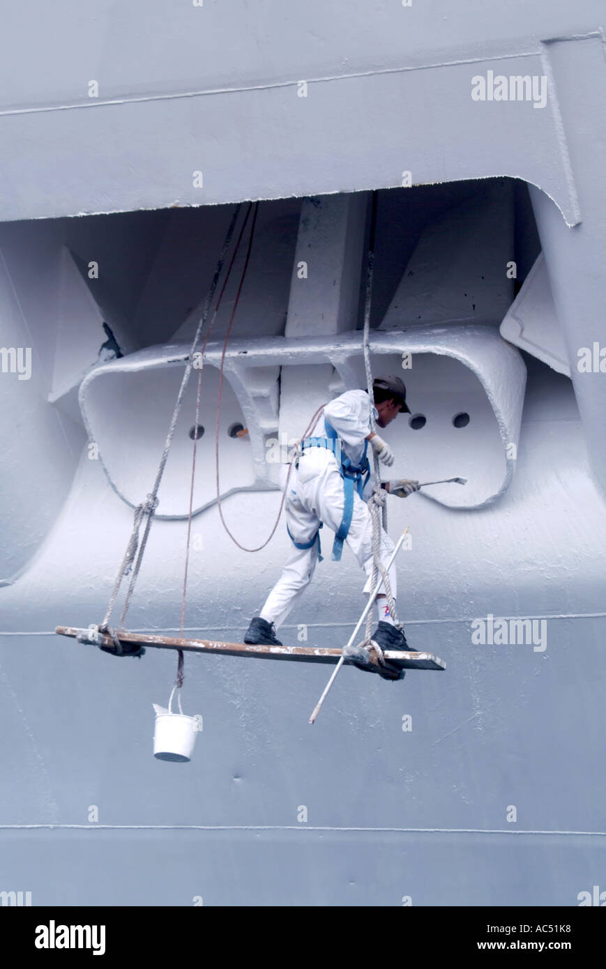 Ajaccio area portuale uomo al lavoro su strette listone verniciatura carter di ancoraggio di ormeggiata la nave di crociera Foto Stock
