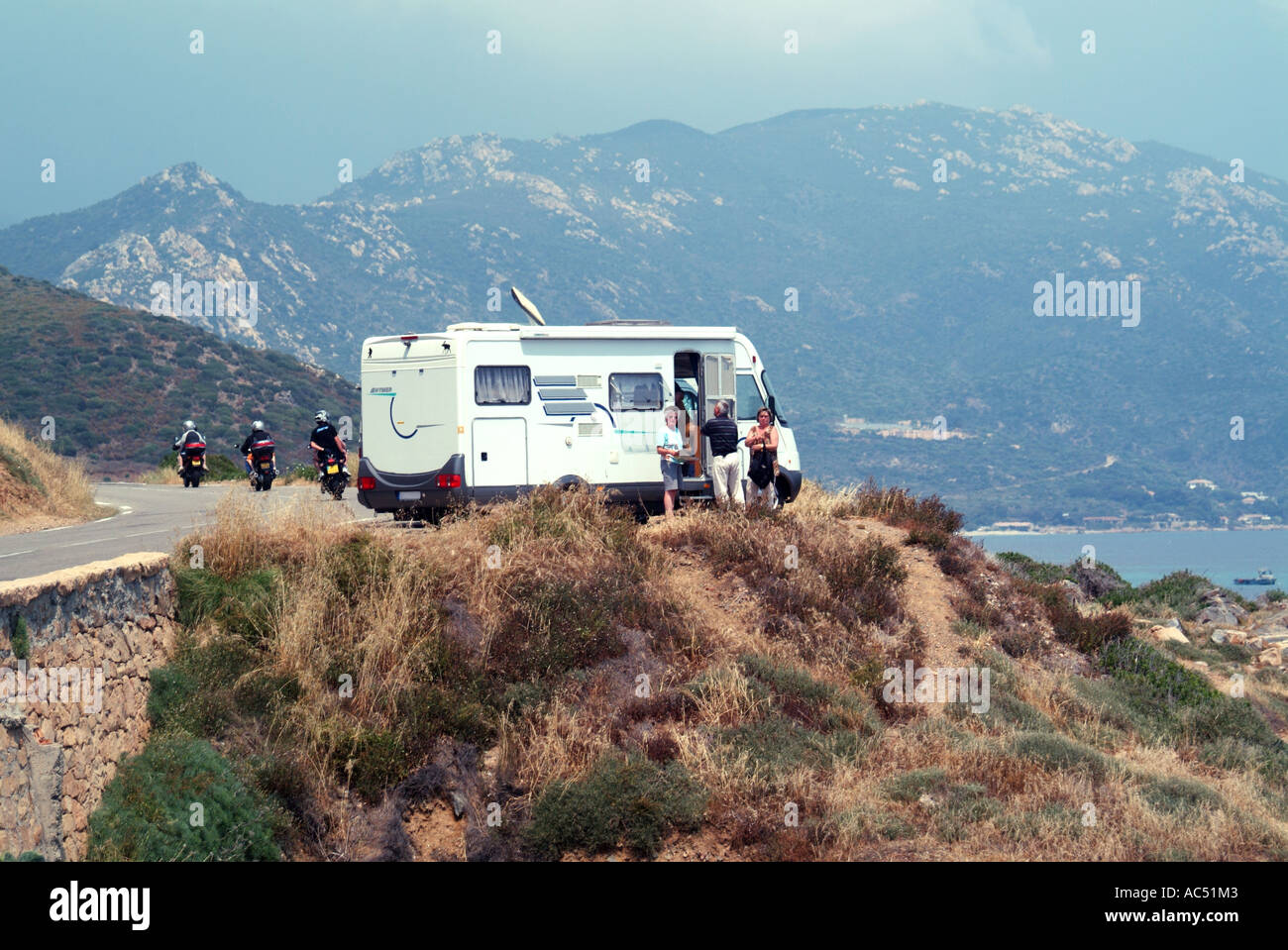 Strada costiera da Ajaccio vicino alle isole Sanguinaires con camper viaggiatori in piedi fuori e paesaggio collinare oltre Ajaccio Corsica Francia Foto Stock