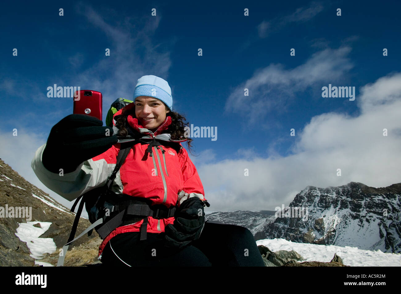 Donna di scattare una foto su un rosso telefono con fotocamera in montagna Foto Stock