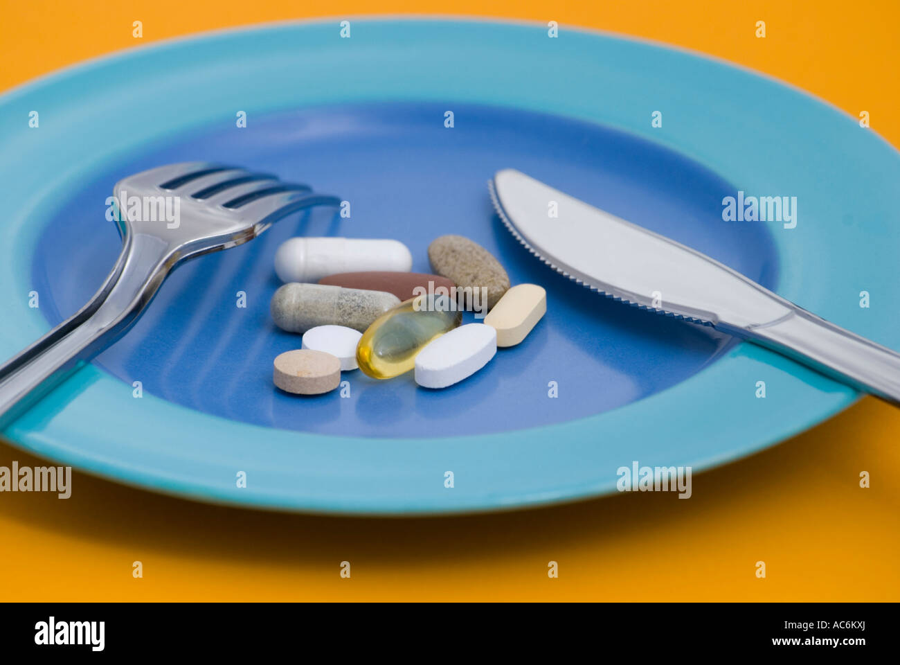 Pillole di vitamine e integratori dietetici sulla piastra con posate Foto Stock