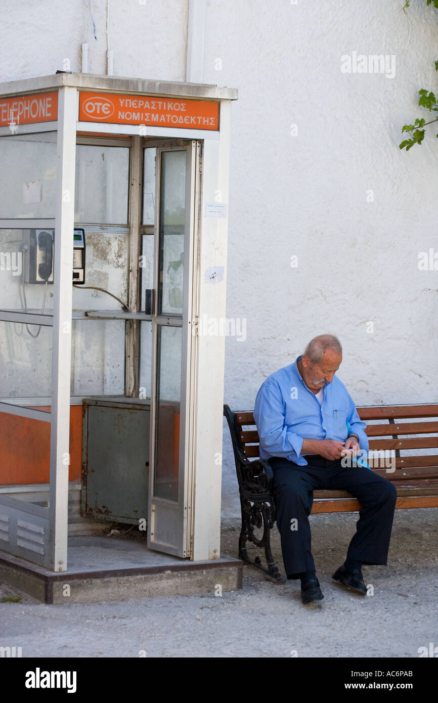 Uomo greco conteggiare denaro accanto alla casella Telefono Foto Stock