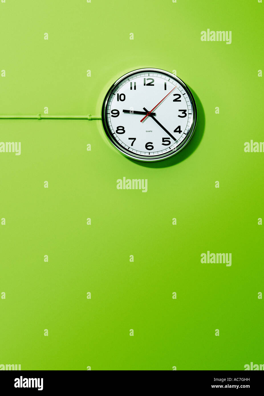 Montato a parete ufficio elettrico orologio contro un calce sfondo verde Foto Stock