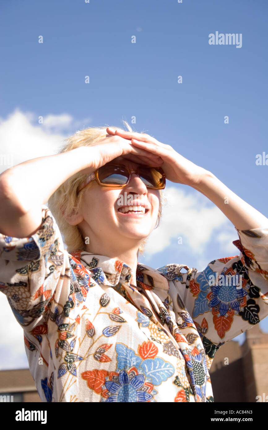 Donna in sun,20's 30's adulto accecato da sole accecante del biondo luminoso blu nubi caucasica giorno di copertura disco volante pieno di sesso femminile Foto Stock
