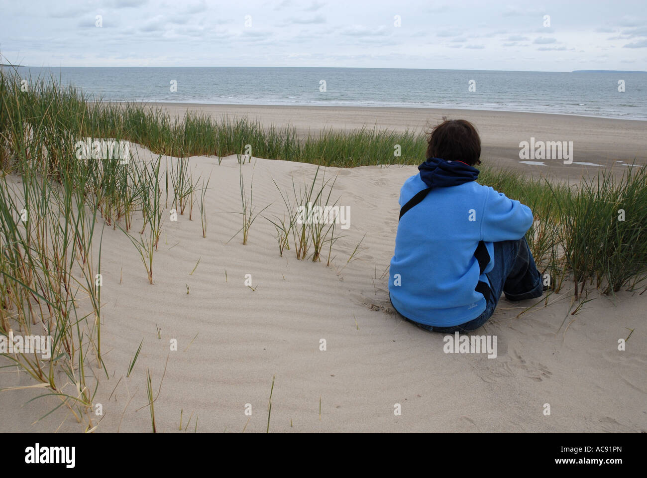 Donna seduta nella duna di sabbia, Harlech, Parco Nazionale di Snowdonia, Gwynedd, il Galles del Nord, Gran Bretagna Foto Stock