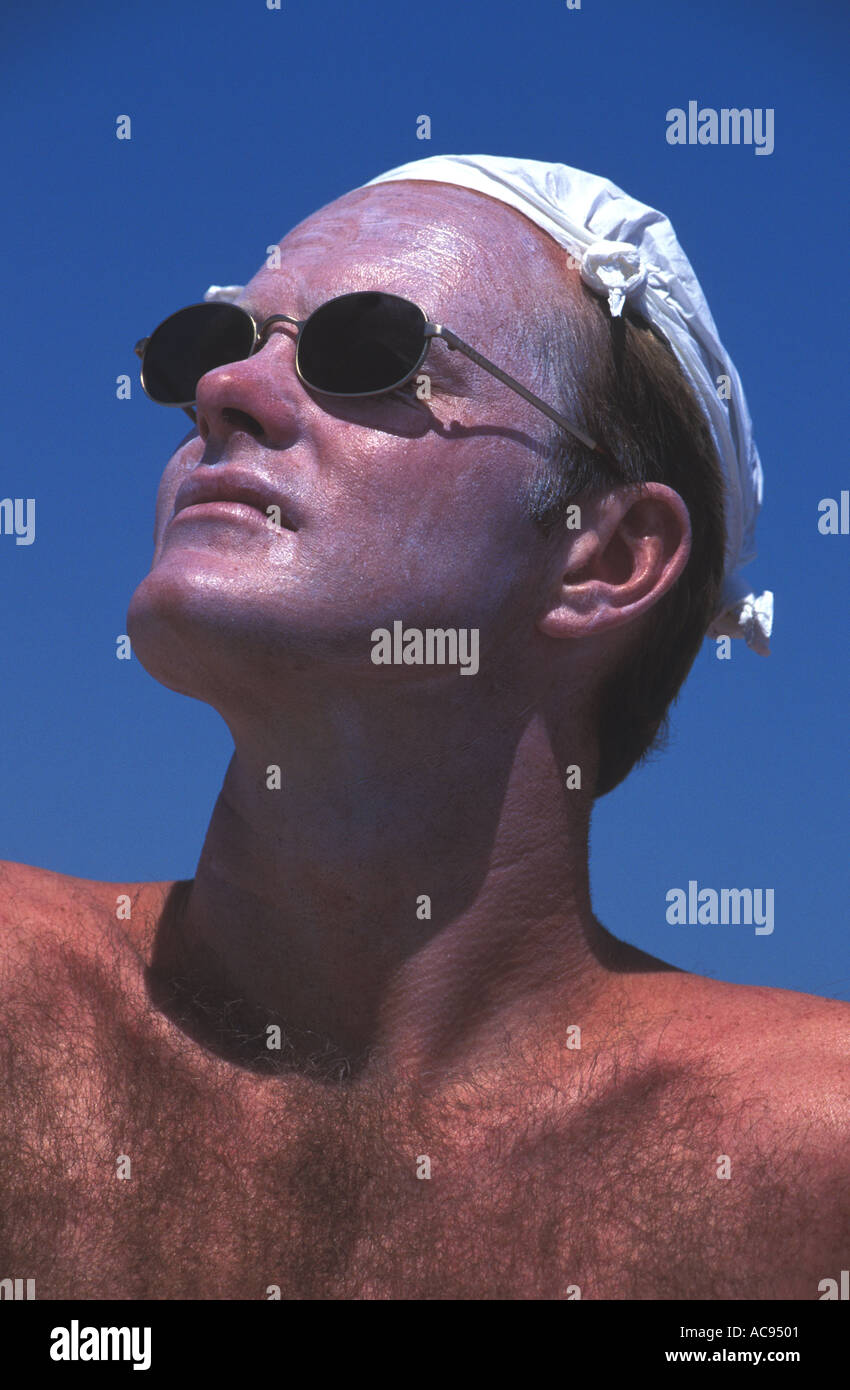 Sunbather inglese con una totale protezione solare sulla faccia di occhiali  da sole e fazzoletto sulla testa Foto stock - Alamy