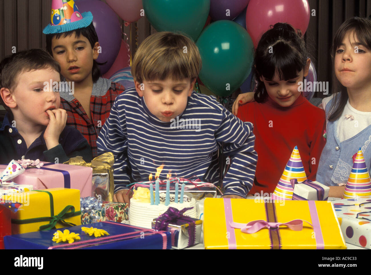 Ragazzo giovane si brucia le candele sulla sua torta di compleanno a una festa Foto Stock