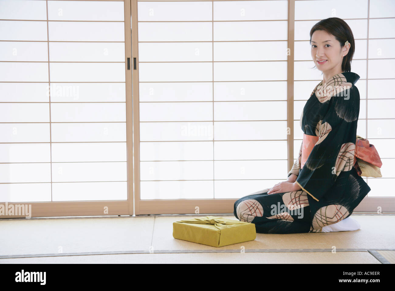 Giovane donna in kimono seduto sul pavimento Foto Stock