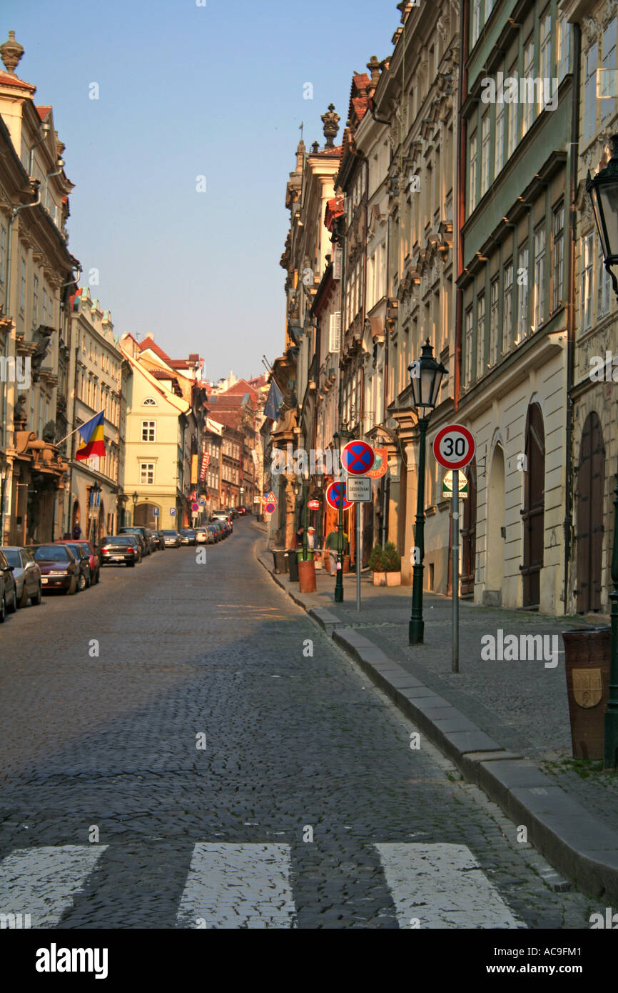 Via Nerudova la mattina presto a Praga, fiancheggiata da edifici storici e lampioni stradali, con auto parcheggiate lungo la strada acciottolata. Foto Stock