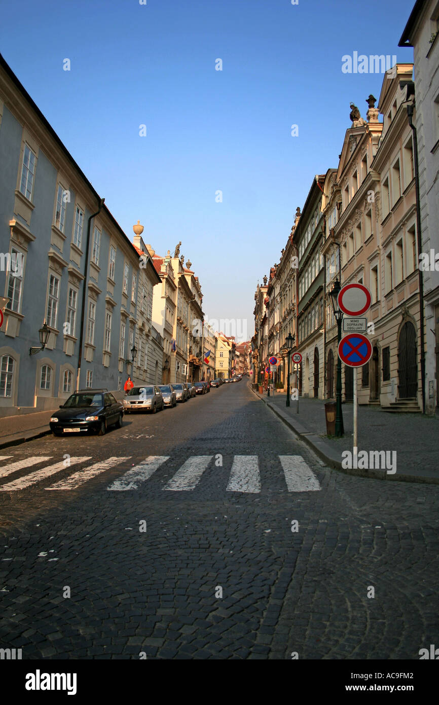 Via Nerudova la mattina presto a Praga, fiancheggiata da edifici storici e lampioni stradali, con auto parcheggiate lungo la strada acciottolata. Foto Stock