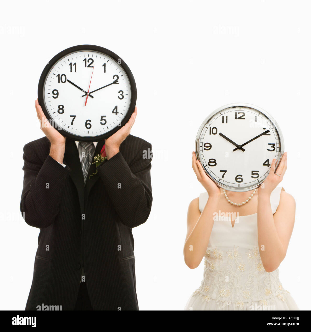 Ritratto di soggetti di razza caucasica lo sposo e la sposa asiatici con orologi che coprono i loro volti Foto Stock