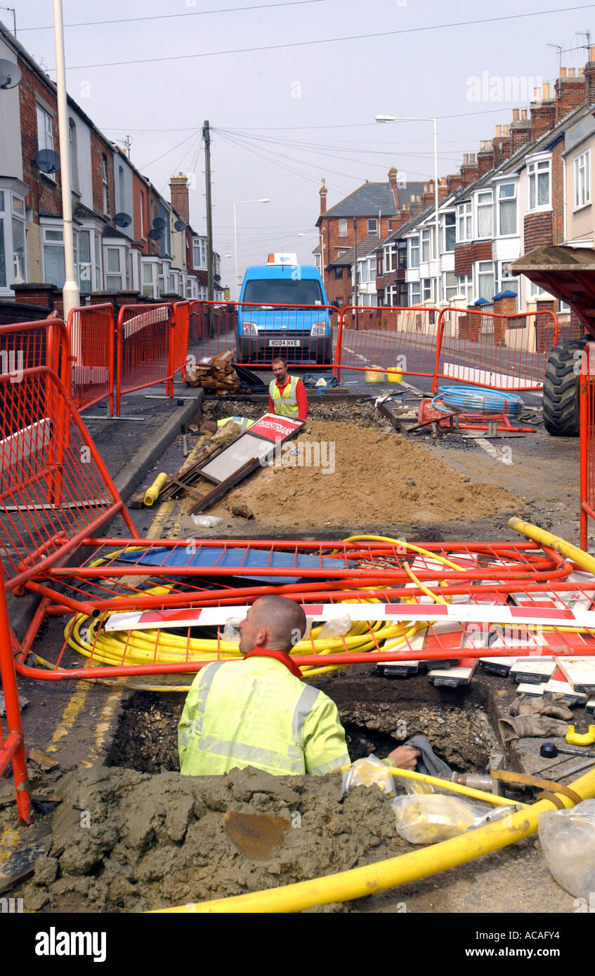 Workman la posa di tubazioni di gas in un foro nella strada, Gran Bretagna REGNO UNITO Foto Stock