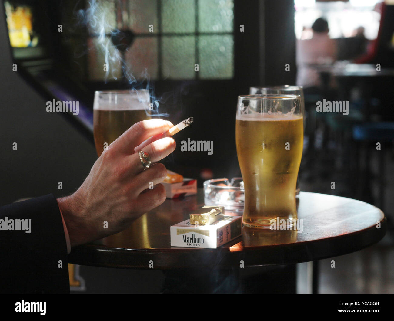 Un fumatore tenendo una sigaretta in un bar nella città di Londra, Regno Unito. Foto Stock