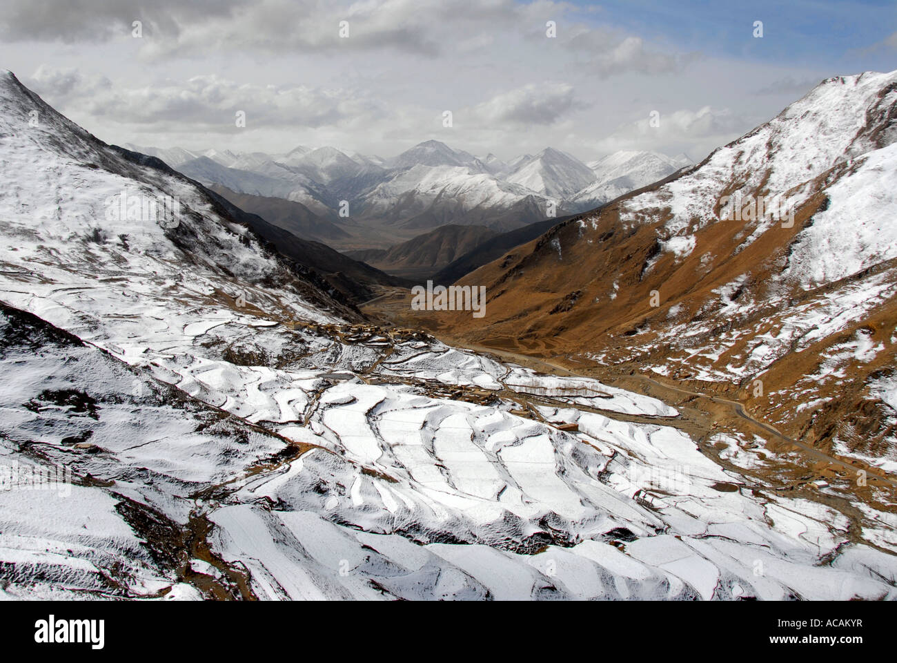 Villaggio sulla coperta di neve pendenza con terrazze e montagne Yerpa Tibet Cina Foto Stock