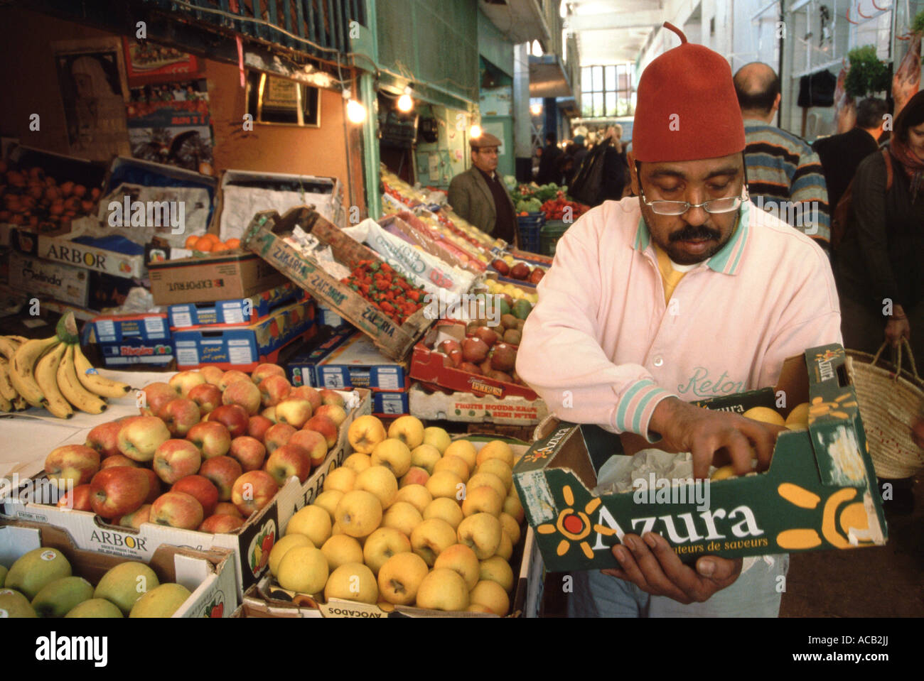 Una frutta & verdura titolare di stallo tende la sua mercanzia al mercato di Ville Nouvelle, Fes, Marocco Foto Stock
