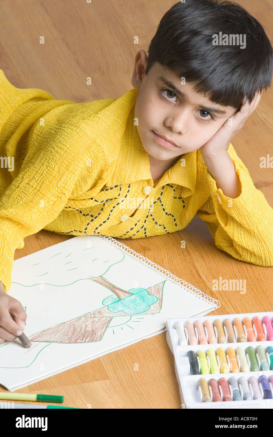 Ritratto di un ragazzo disteso sul pavimento in legno duro e disegno con matita colorata Foto Stock