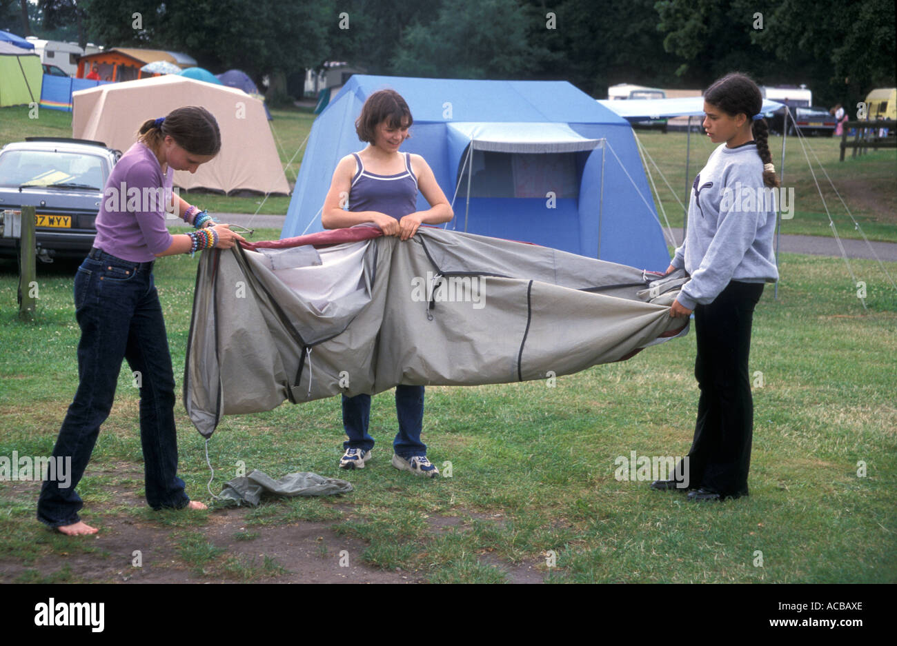 Tre ragazze adolescenti la piegatura tenda dopo uso sul viaggio di campeggio Foto Stock