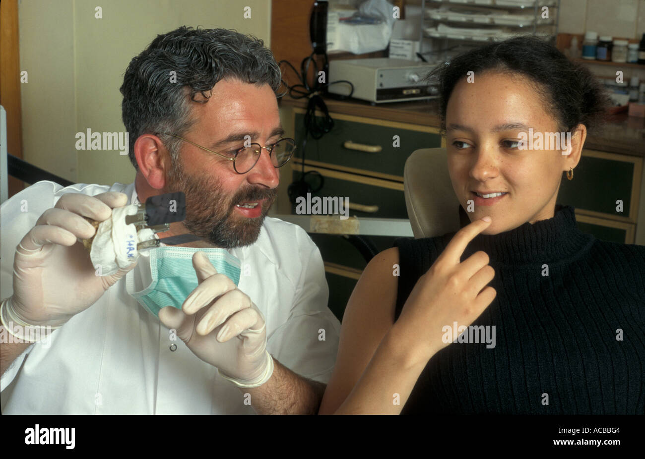Dentista barbuto che mostra il dente X ray alla ragazza adolescente paziente Foto Stock
