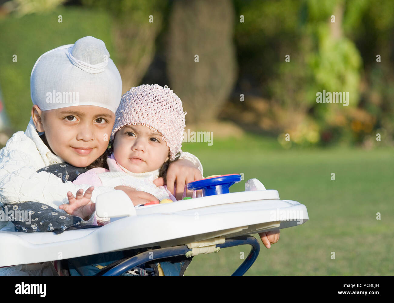 Ritratto di un ragazzo con sua sorella seduta in una baby walker Foto Stock