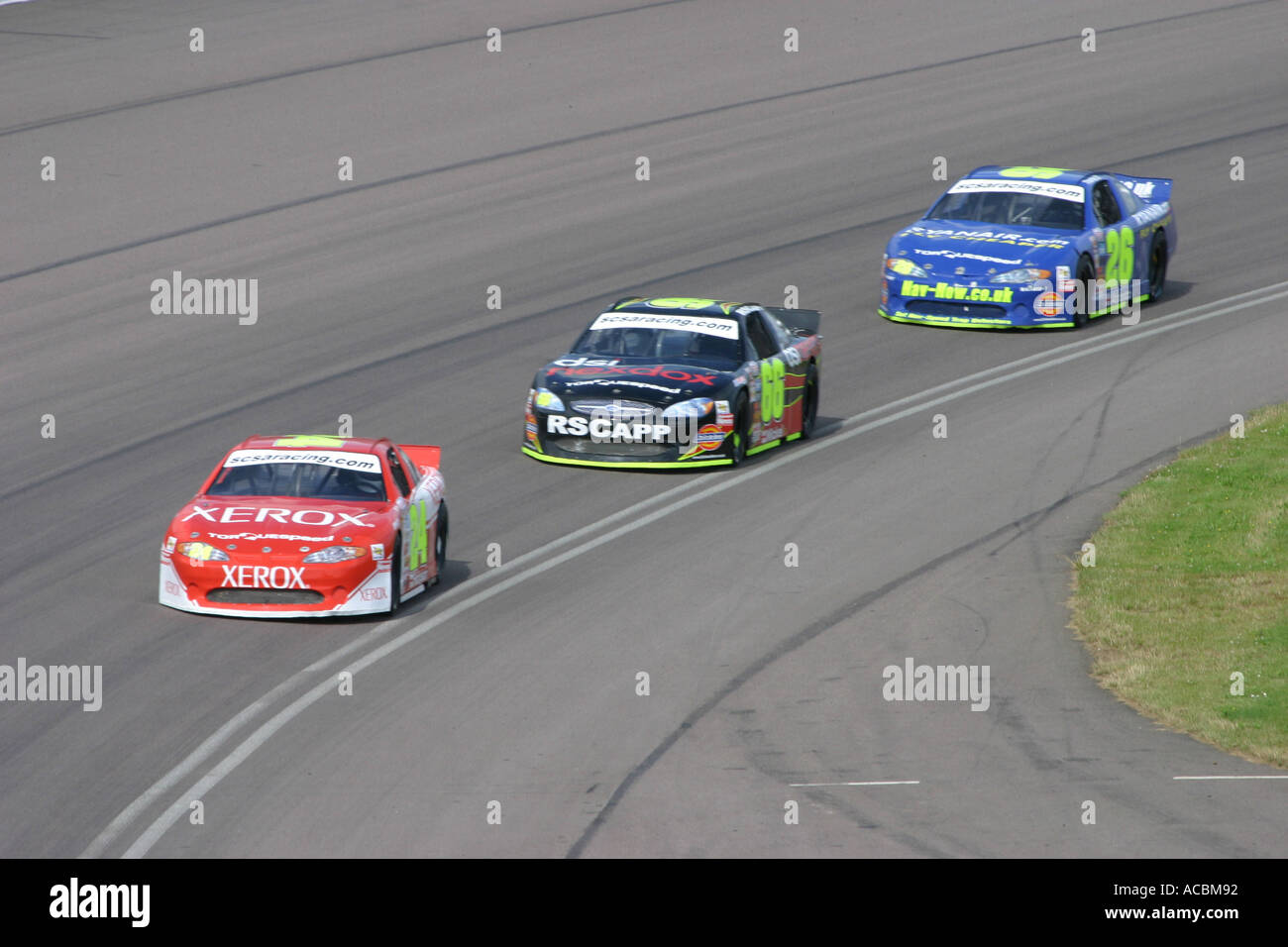 V8 tipo Nascar stock cars racing su un puntato circuito ovale Foto Stock